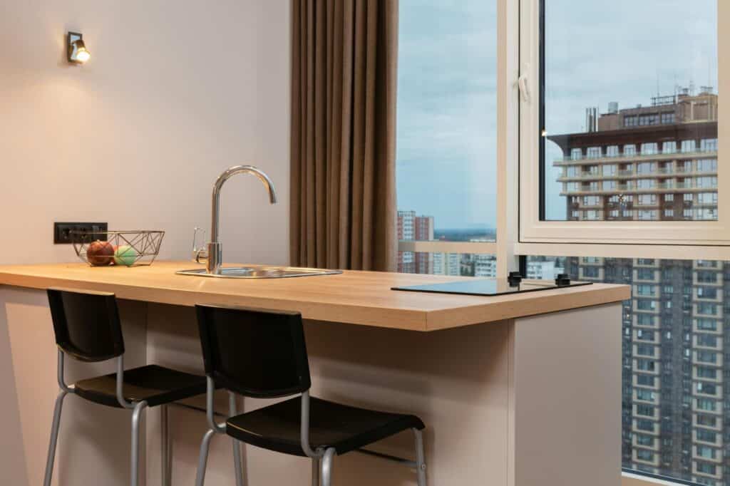 A kitchen in a modern flat with windows overlooking modern residential buildings