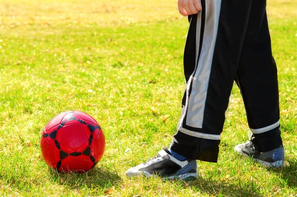 A schoolboy is playing football on a sunny day at school