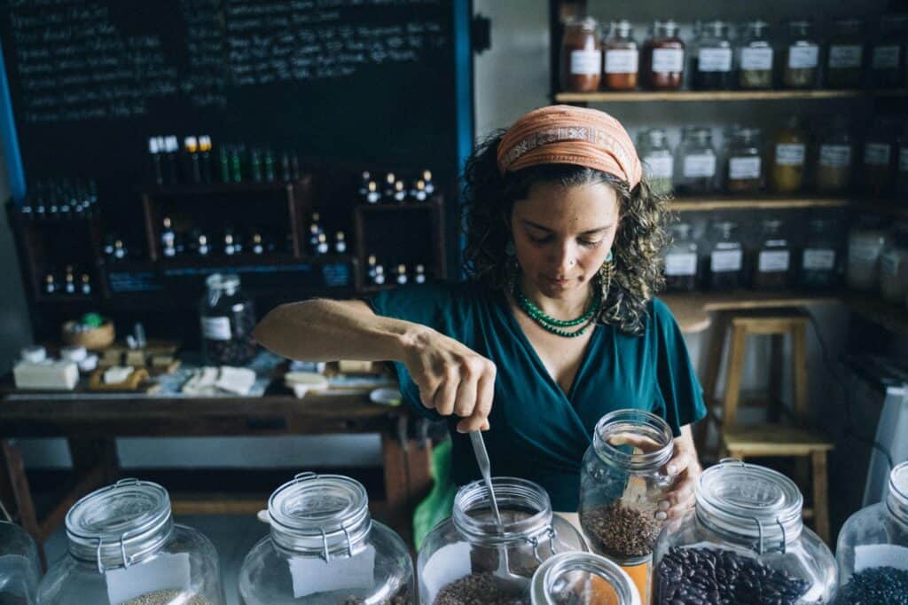 A woman scooping beans from a transparent jar in a wellness shop