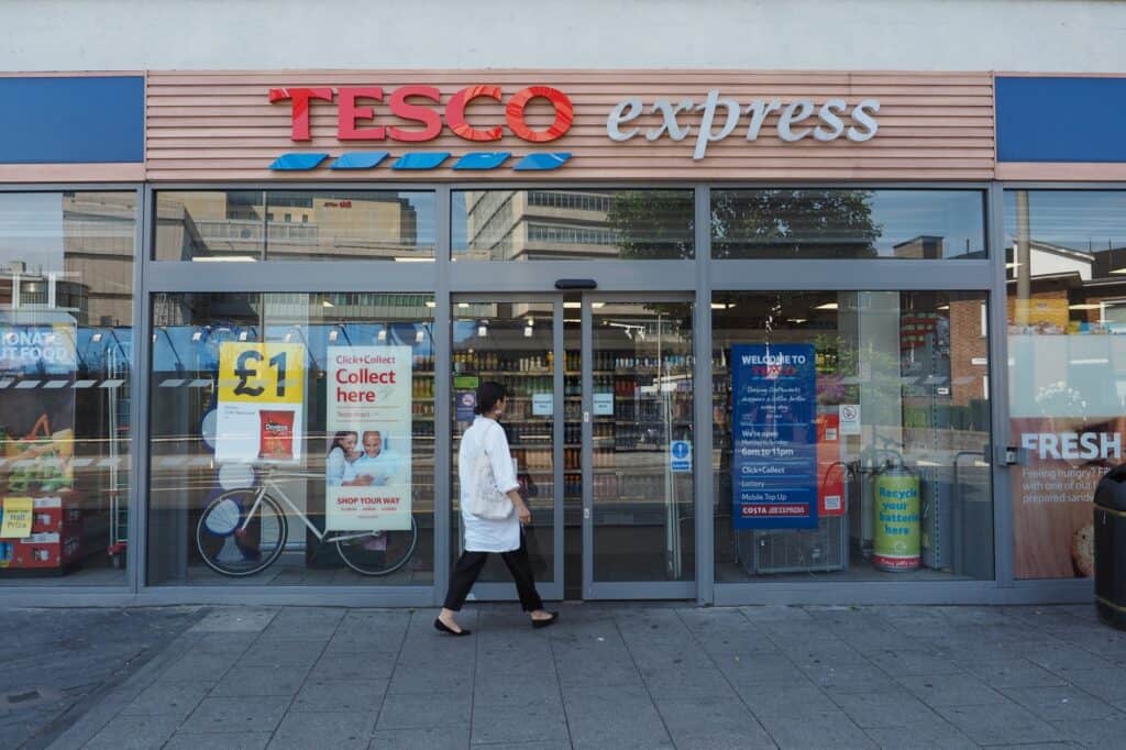 A woman walking toward the Tesco Express storefront