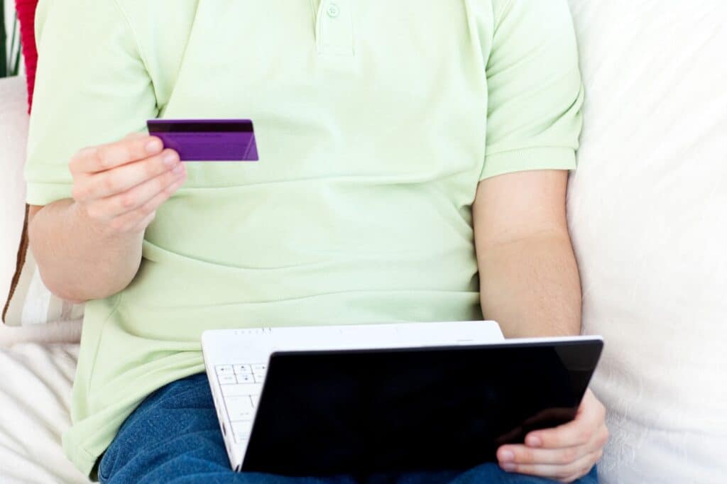 Cropped image of a young man holding a credit card and laptop in the concept of updating his address with financial institutions